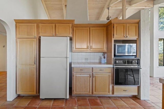 kitchen featuring tile countertops, black oven, wooden ceiling, backsplash, and white refrigerator