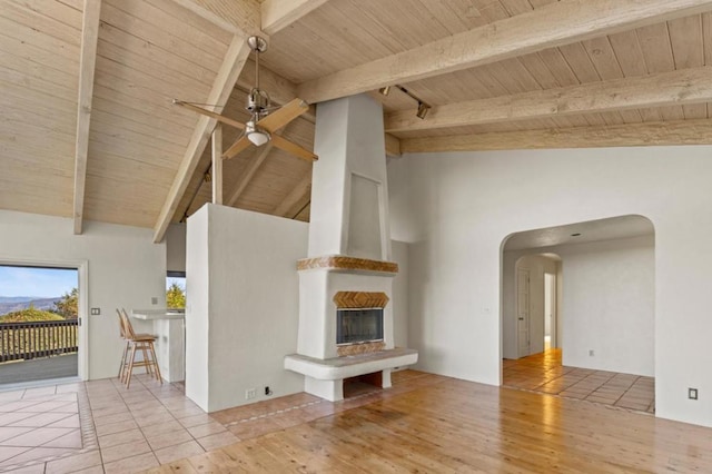 unfurnished living room with wooden ceiling, a large fireplace, beam ceiling, and ceiling fan