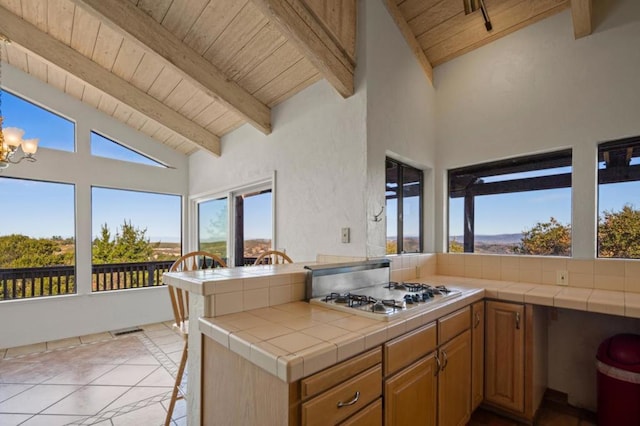 kitchen featuring tile counters, stainless steel gas cooktop, kitchen peninsula, and wood ceiling