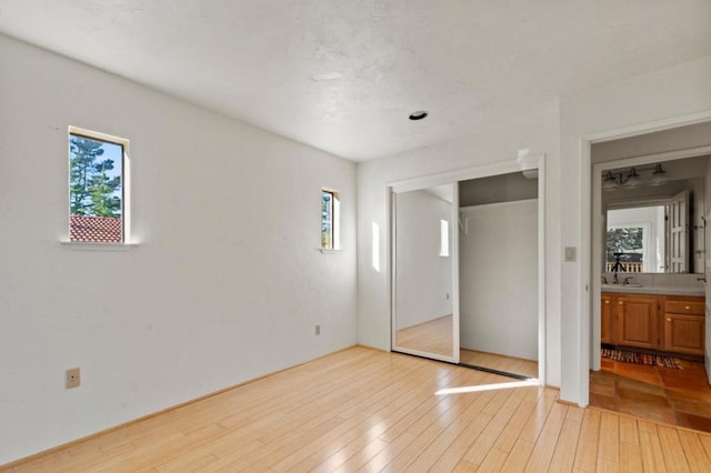 unfurnished bedroom featuring a closet, sink, and light hardwood / wood-style floors