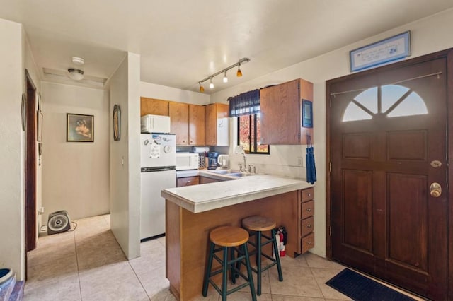 kitchen featuring light tile patterned floors, sink, kitchen peninsula, and white appliances