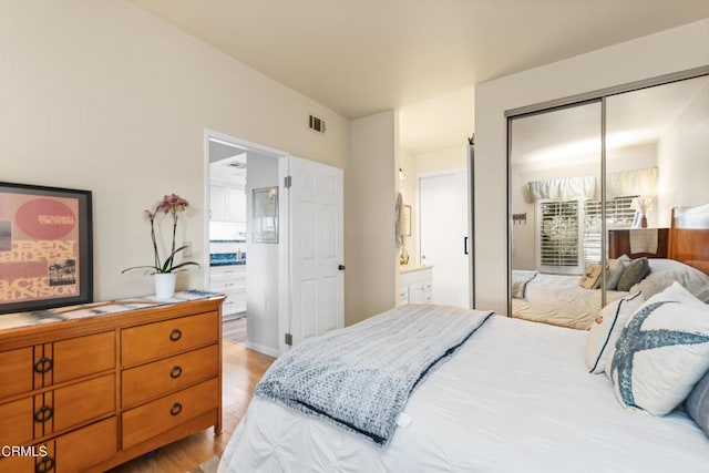 bedroom featuring ensuite bathroom, a closet, and light hardwood / wood-style floors