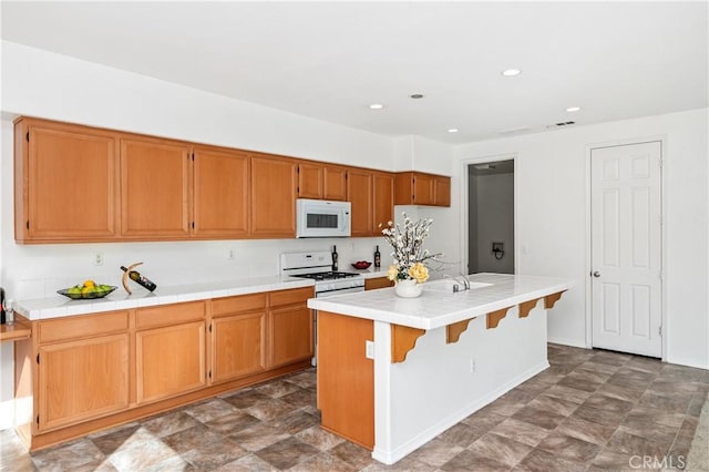 kitchen with sink, white appliances, a center island with sink, and tile counters