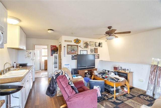 living room featuring dark hardwood / wood-style flooring, ceiling fan, and sink