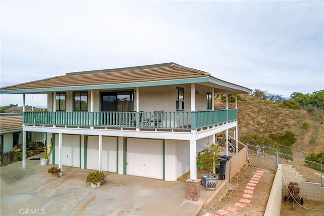 rear view of house featuring a balcony and a garage