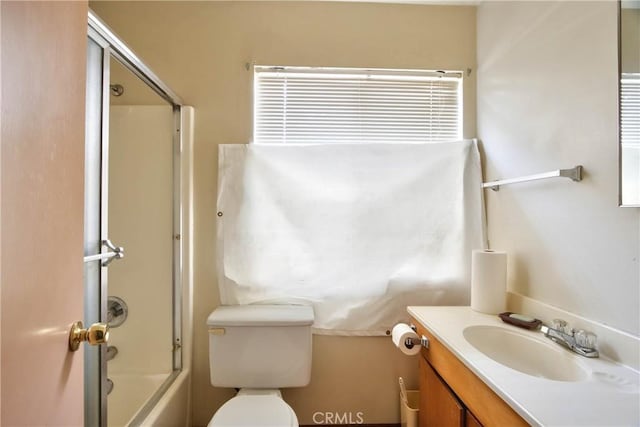 full bathroom featuring vanity, bath / shower combo with glass door, and toilet