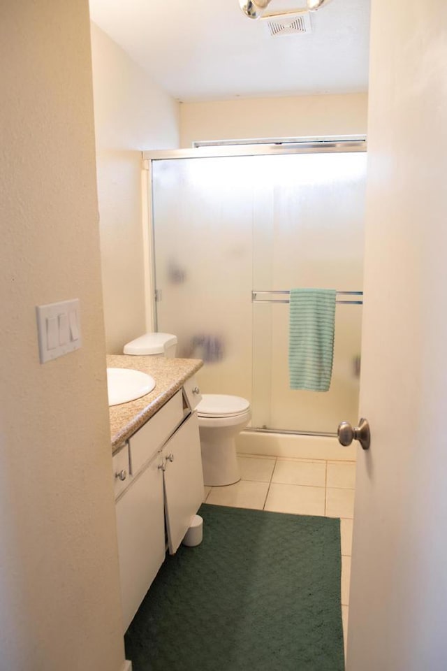 bathroom with toilet, walk in shower, vanity, and tile patterned flooring