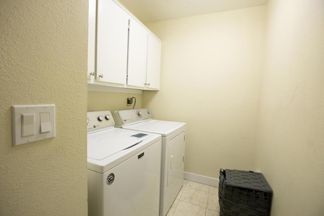 washroom featuring washing machine and dryer, cabinets, and light tile patterned flooring