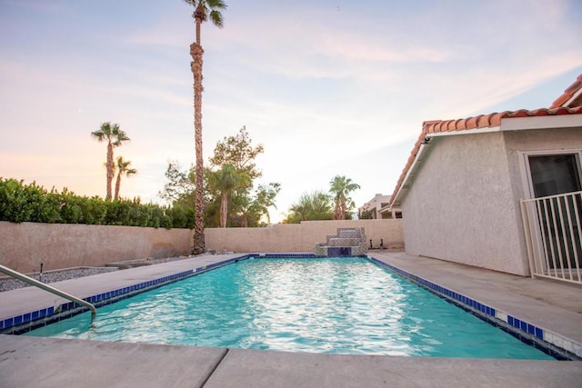 pool at dusk featuring a patio