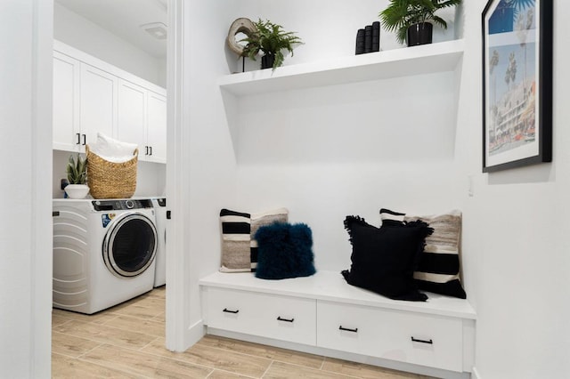 clothes washing area with cabinets, light wood-type flooring, and washer / dryer