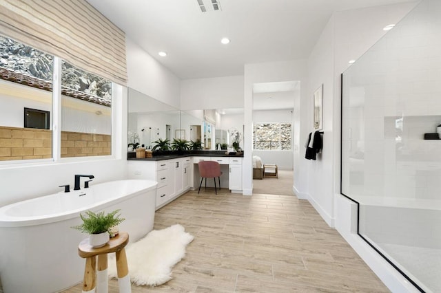 bathroom with plus walk in shower, wood-type flooring, and vanity