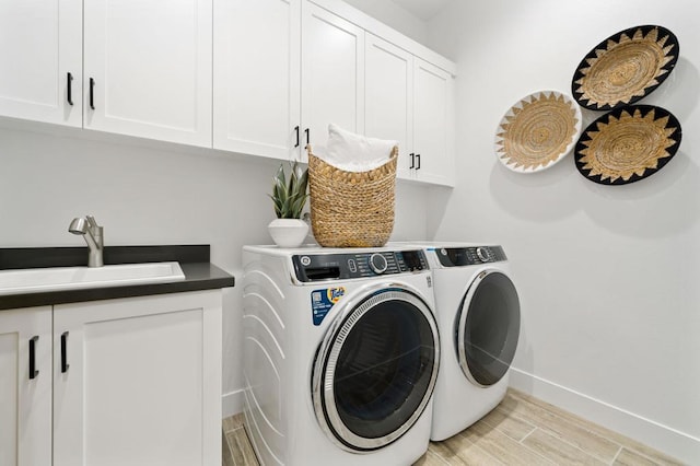 clothes washing area with separate washer and dryer, sink, cabinets, and light hardwood / wood-style flooring