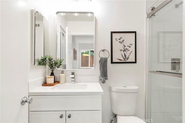 bathroom featuring vanity, an enclosed shower, and toilet