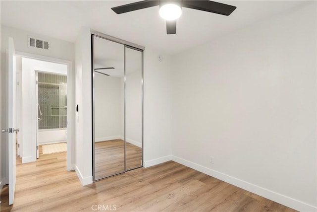 unfurnished bedroom featuring ceiling fan, light wood-type flooring, and a closet