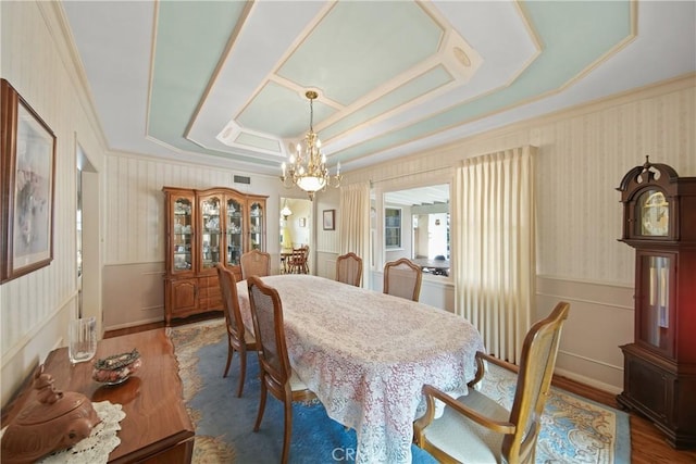 dining area with a raised ceiling, dark hardwood / wood-style floors, and an inviting chandelier