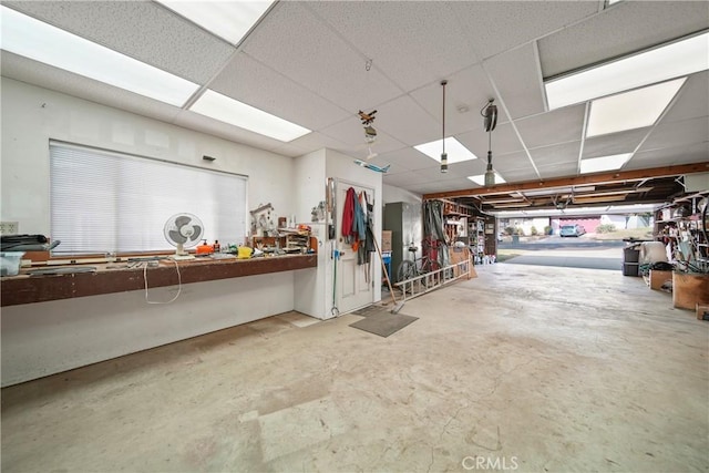 interior space with a workshop area, a paneled ceiling, and concrete flooring