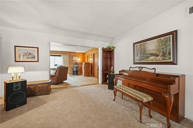 living area with wood walls and light carpet