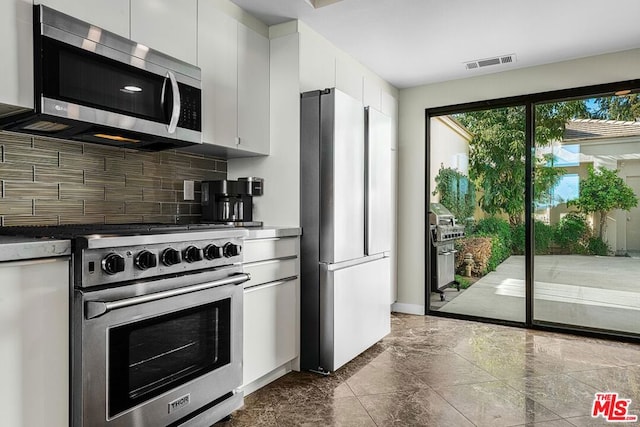 kitchen with decorative backsplash, white cabinetry, and stainless steel appliances