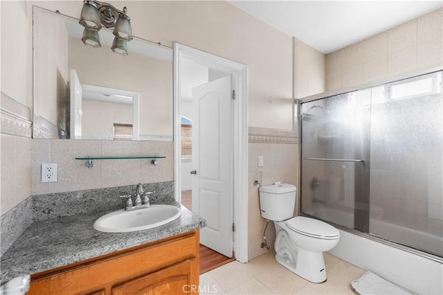 bathroom featuring toilet, tile walls, tile patterned floors, and vanity