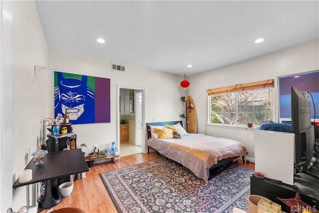 bedroom featuring ensuite bathroom and hardwood / wood-style flooring