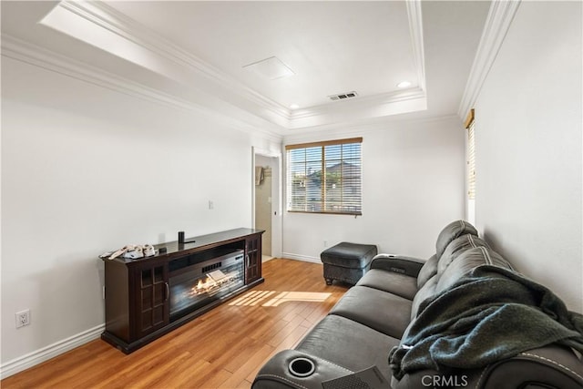 living room featuring hardwood / wood-style floors, crown molding, and a raised ceiling