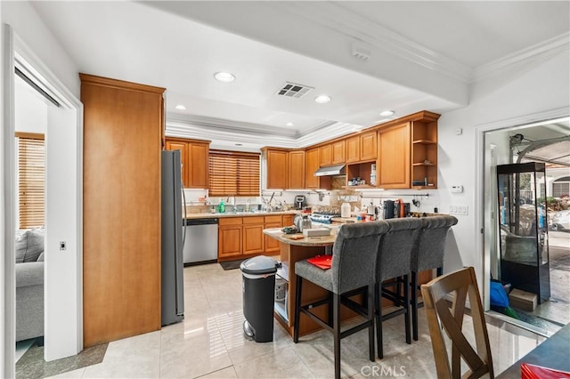 kitchen featuring light tile patterned flooring, appliances with stainless steel finishes, ornamental molding, and a breakfast bar