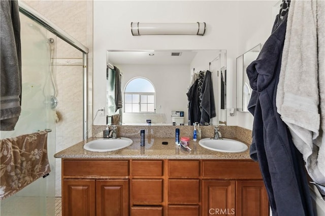 bathroom with a shower with shower door and vanity