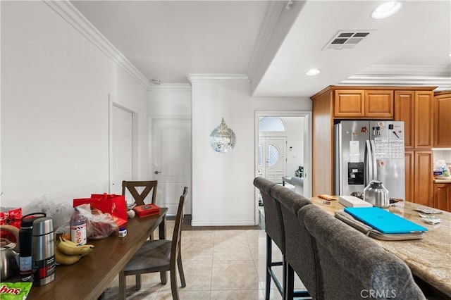 kitchen featuring stainless steel refrigerator with ice dispenser, light tile patterned flooring, light stone counters, and ornamental molding