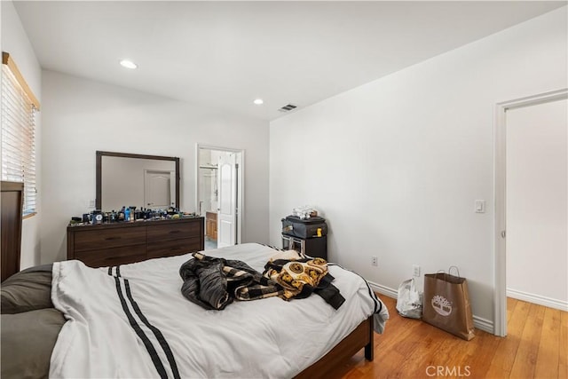 bedroom with light hardwood / wood-style flooring and ensuite bath