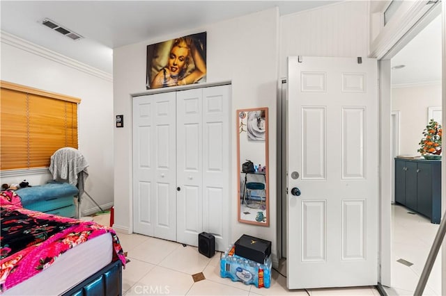 bedroom with a closet, light tile patterned floors, and crown molding