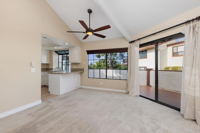 unfurnished living room featuring ceiling fan, sink, light carpet, and vaulted ceiling with beams