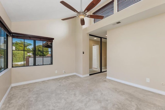 empty room with high vaulted ceiling, light colored carpet, and ceiling fan