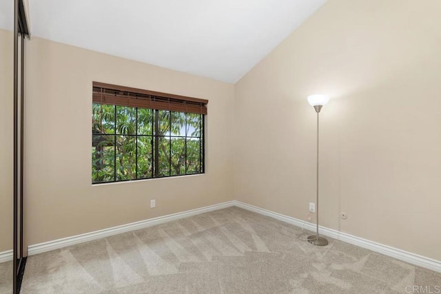 carpeted spare room featuring lofted ceiling