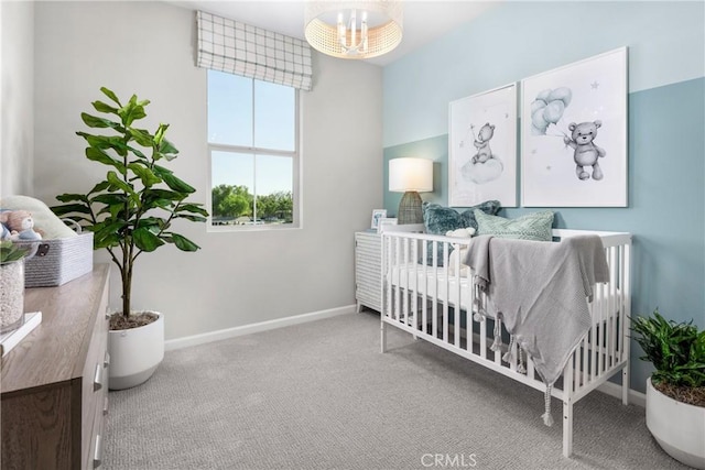 carpeted bedroom with a notable chandelier and a nursery area