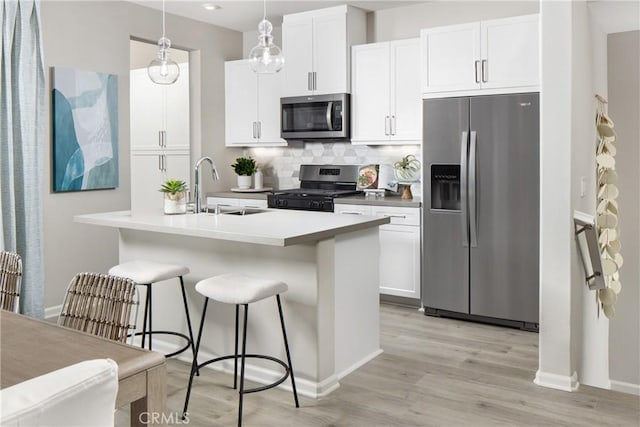 kitchen featuring decorative light fixtures, sink, white cabinetry, and stainless steel appliances