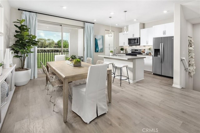 dining space with light wood-type flooring and sink