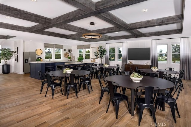 dining space with beam ceiling, coffered ceiling, and light wood-type flooring