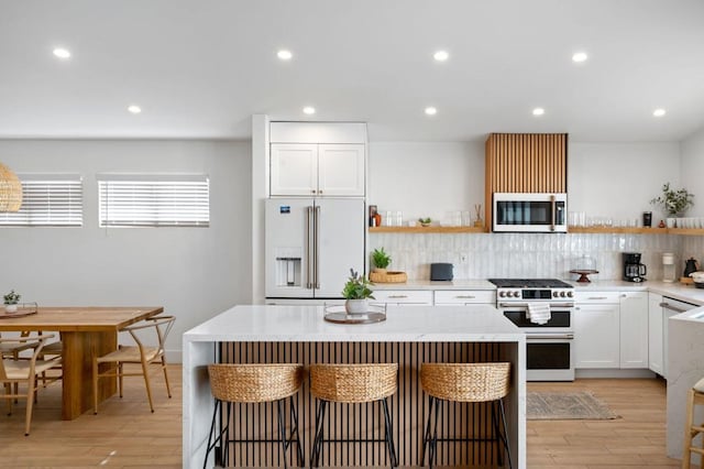 kitchen featuring a kitchen bar, white cabinets, a kitchen island, and high end appliances