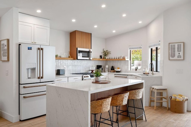 kitchen with white cabinetry, a kitchen bar, stainless steel appliances, and a kitchen island