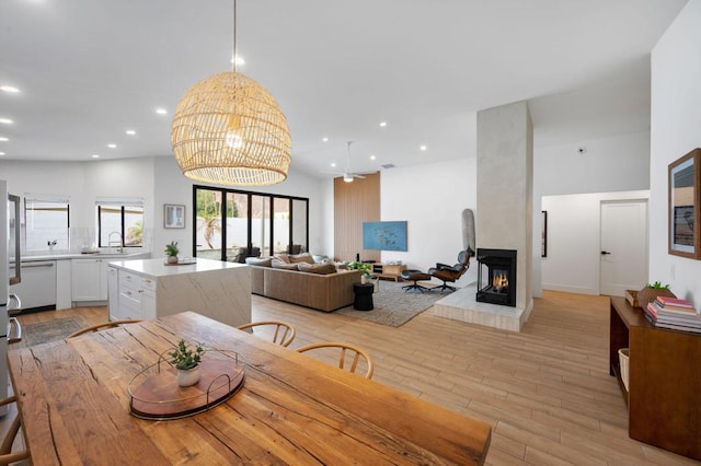 dining space featuring a multi sided fireplace, sink, and light hardwood / wood-style flooring