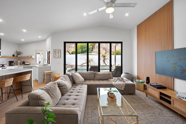 living room featuring light wood-type flooring, ceiling fan, lofted ceiling, and sink