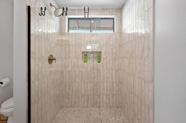 bathroom featuring toilet and a tile shower