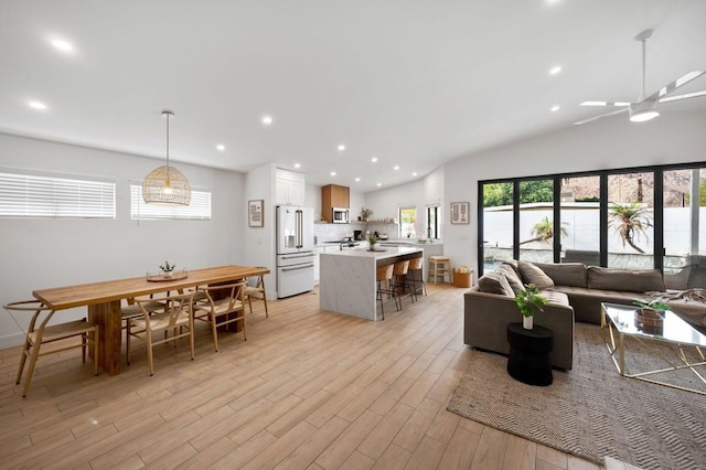 living room featuring ceiling fan, light hardwood / wood-style floors, and lofted ceiling