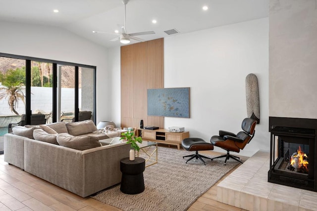 living room featuring a multi sided fireplace, light hardwood / wood-style floors, lofted ceiling, and ceiling fan