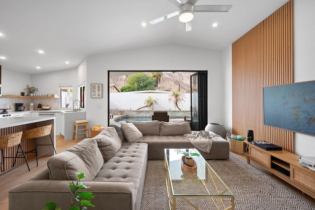 living room featuring vaulted ceiling, ceiling fan, light hardwood / wood-style flooring, and sink