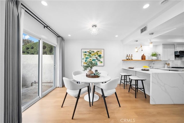 dining area with a chandelier, light hardwood / wood-style floors, and sink