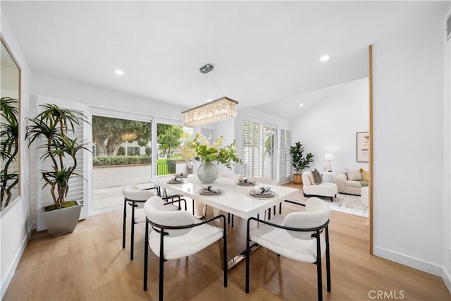 dining space featuring an inviting chandelier, vaulted ceiling, and light wood-type flooring