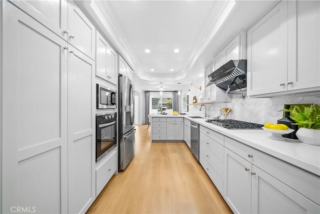 kitchen with sink, stainless steel appliances, white cabinets, exhaust hood, and light wood-type flooring