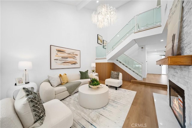 living room with a fireplace, a towering ceiling, light hardwood / wood-style flooring, and beamed ceiling