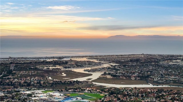 aerial view at dusk featuring a water view